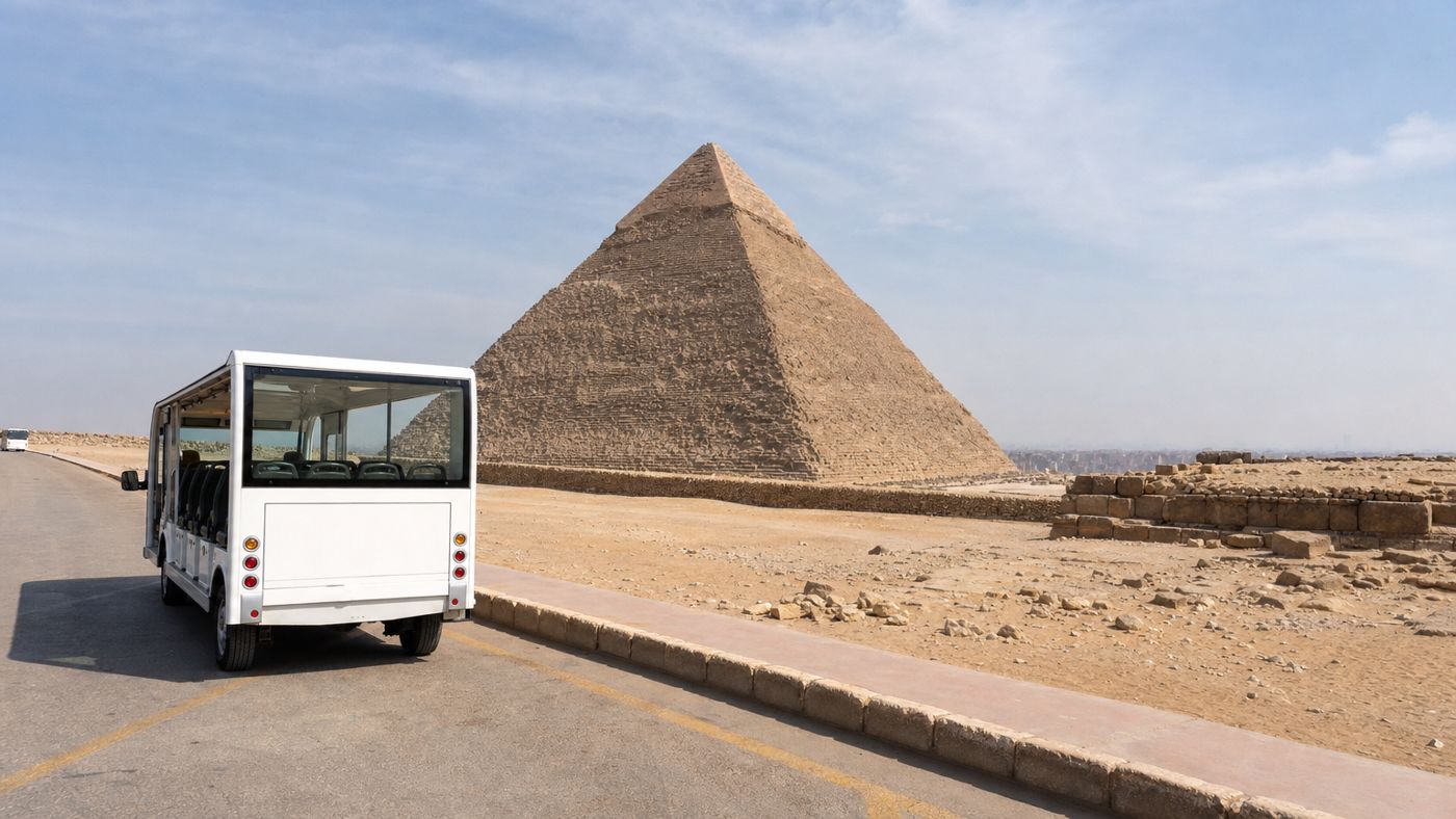 Chemin pavé sur le plateau de Gizeh avec un bus électrique à l'arrêt, une pyramide en arrière-plan