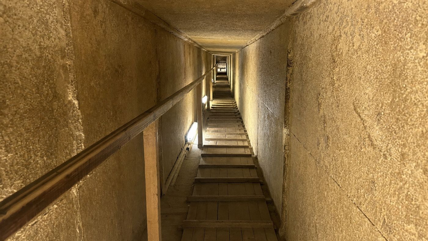 Visitors walking bent over in the ascending passage of the Great Pyramid of Khufu