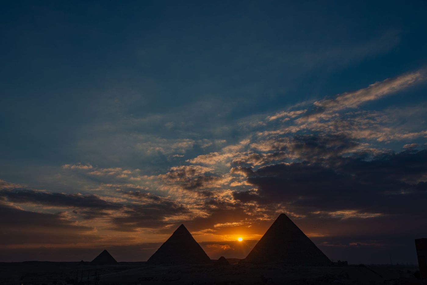 The three pyramids of Giza in morning light, diagonally staggered in front of the desert
