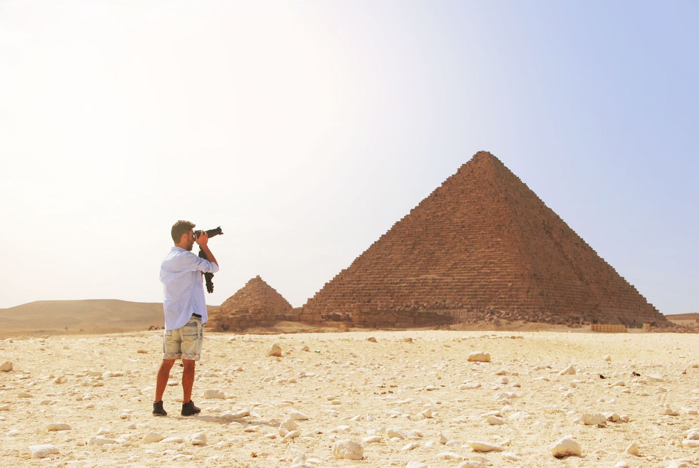 Film crew with camera and tripod in front of a pyramid on the Giza Plateau