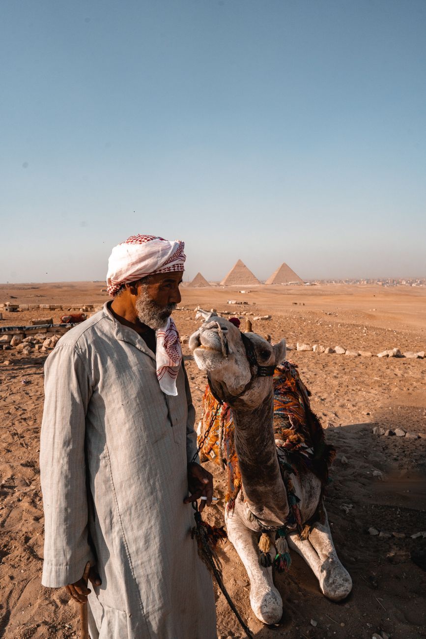 Deux voyageurs avec un guide au pied d'une pyramide, personne d'autre en vue