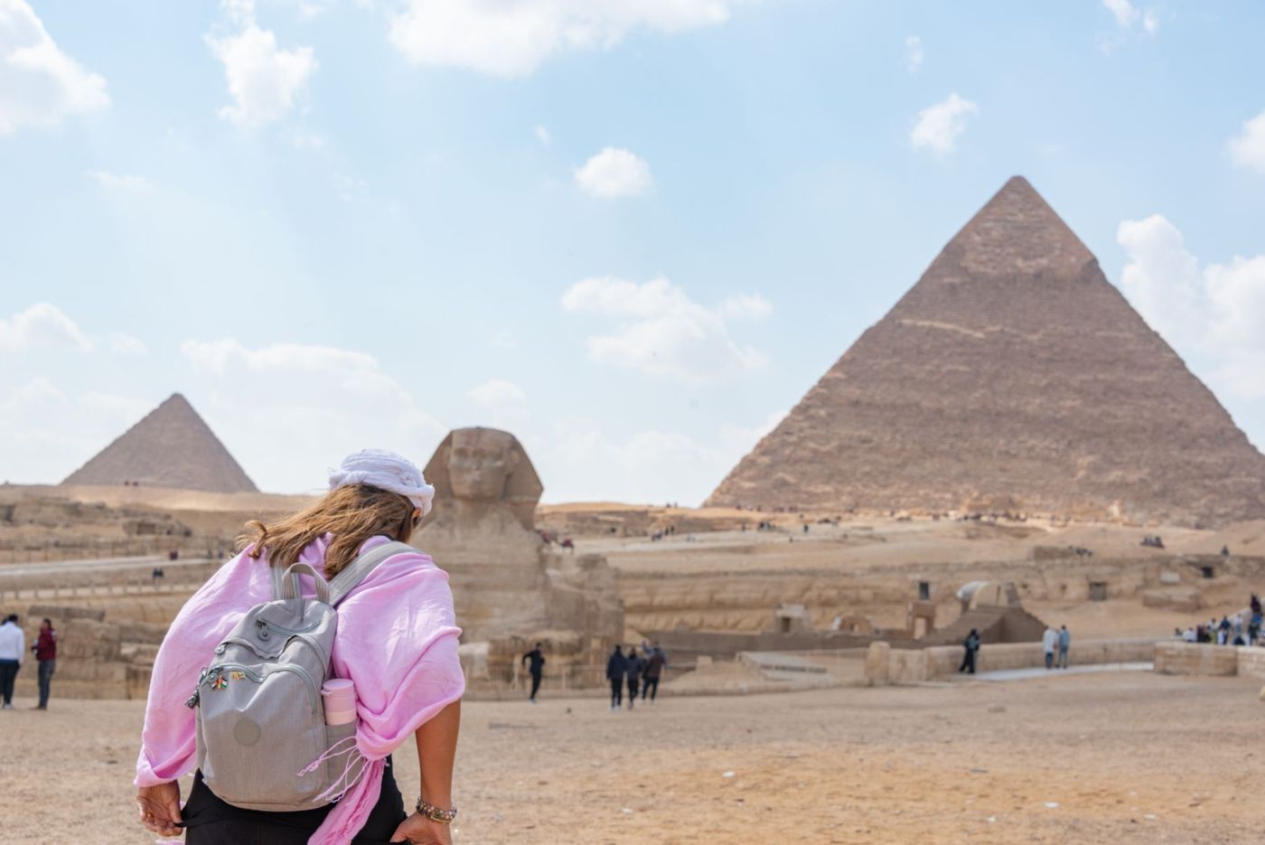 Donna in piedi da sola sul sentiero dell'altopiano di Giza mentre fotografa una piramide