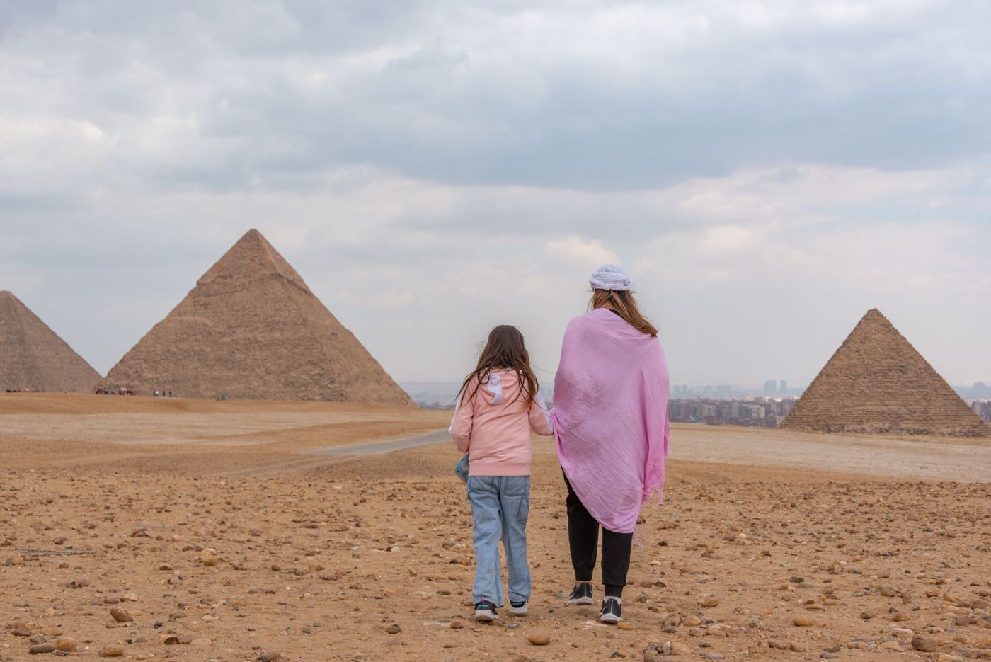 Kind steht vor einer Steinlage am Fuß einer Pyramide, der Block reicht ihm über den Kopf