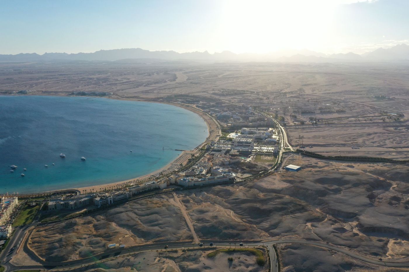 Aerial view of a bay on the Red Sea, a narrow strip of hotels, behind it open desert